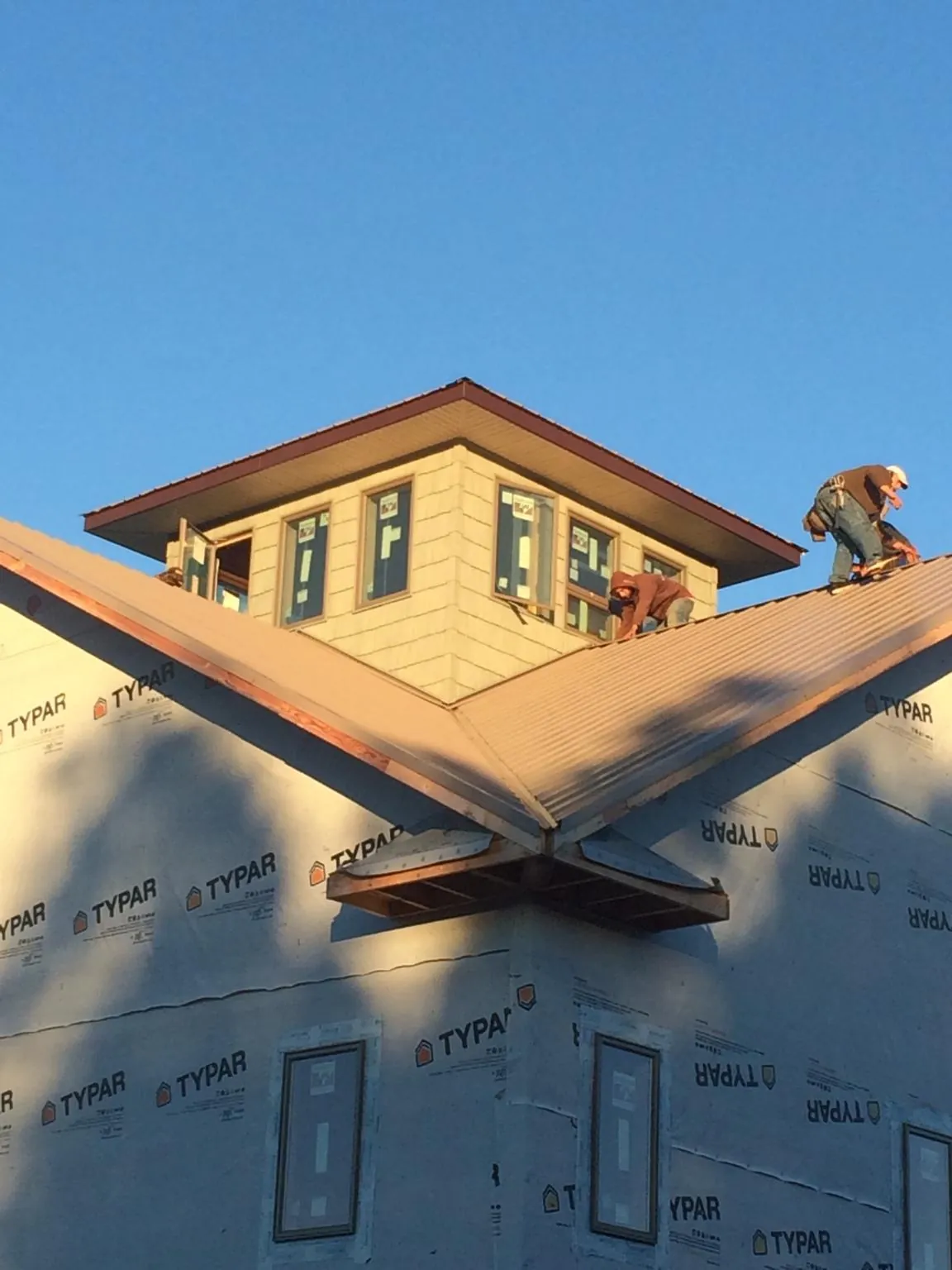 Roofers working around a rooftop cupola on a new metal roof at sunset — Roof Waterproofing in Middletown by Roofing Brothers
